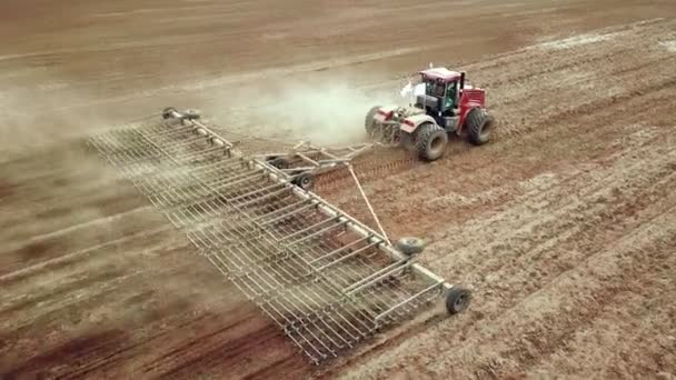 Luchtfoto van een boer in trekker die land bereidt op landbouwgrond. Top down view witte trekker ploegen velden, het voorbereiden van land voor het zaaien. — Stockvideo