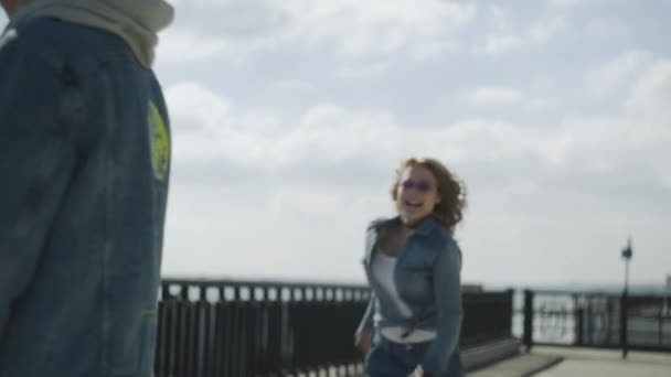 Молодая женщина бежит к мужчине и прыгает к его спине — стоковое видео
