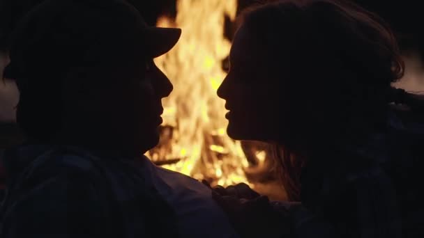 Silhuetter av unga par ligger nära brasan och kyss, utomhus — Stockvideo