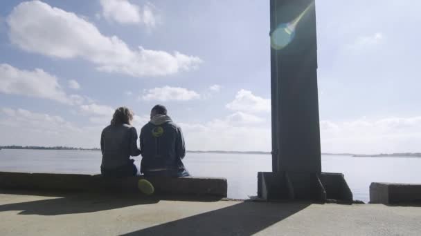 Vista posterior de la hermosa pareja romántica de hombre y mujer se sienta cerca del río — Vídeo de stock