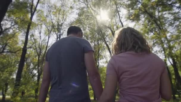 Happy caucasian family walks towards sun in city park at sunset. — Stock Video