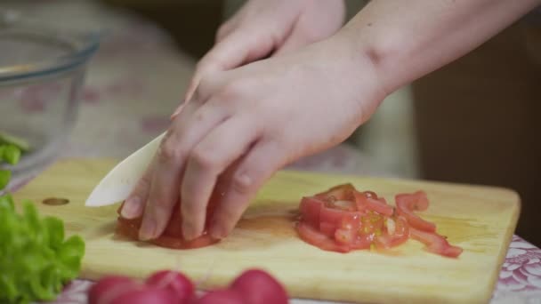 Шеф-повар режет свежие овощи. Женщина с помощью кухонного ножа режет свежие помидоры — стоковое видео