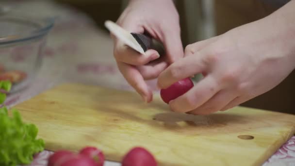 Kucharka kroi świeże warzywa. Kobieta używa kuchennego noża do cięcia świeżej rzodkiewki — Wideo stockowe