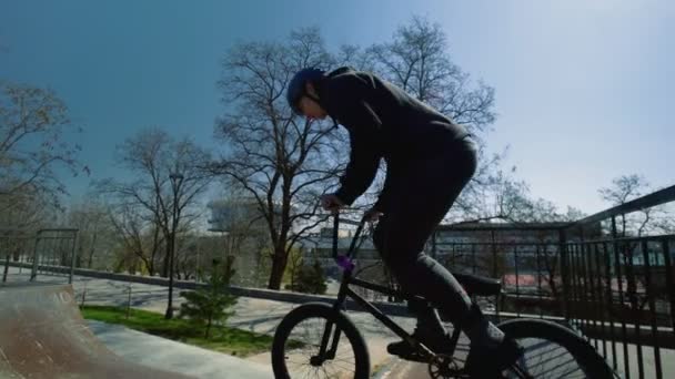 Genç bir BMX sürücüsü boş bir kaykay parkında pratik yapıyor. — Stok video