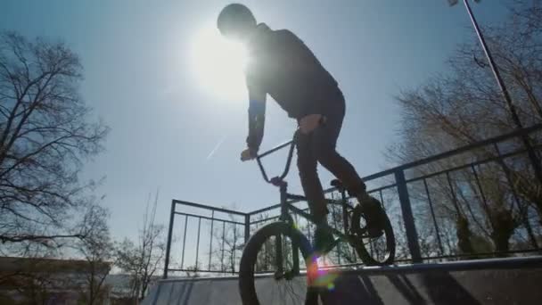 Um piloto BMX montando em rampas e realizando truques no parque de skate — Vídeo de Stock