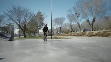 Genç bir BMX sürücüsü kaykay parkında boru numaraları yapıyor..