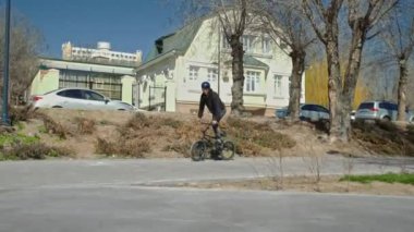 Genç bir bmx binicisi kaykay parkında boruların üzerinden döner..