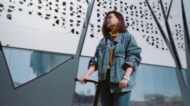 Motosikletli, kot ceketli genç Asyalı kadın arkadaşlarına el sallıyordu.