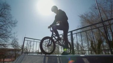 Gün batımında ekstrem parkta numaralar yapan genç bir BMX sürücüsü.