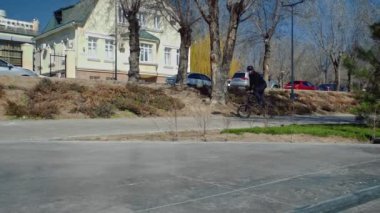 Genç bir bmx binicisi kaykay parkında boruların üzerinden döner..