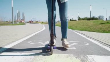 Bir yaz parkında mobiletle gezen kot pantolonlu kadınların bacaklarını kapat.