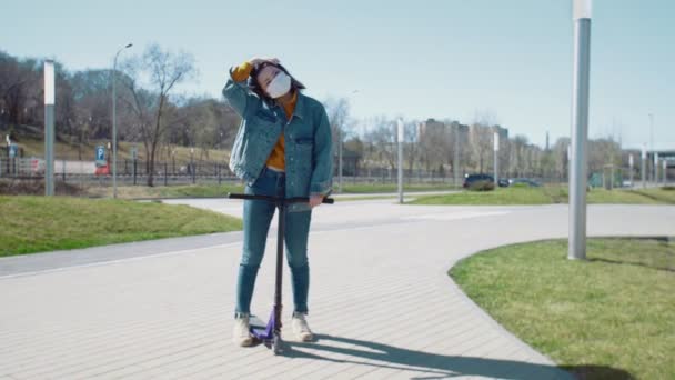 Jonge aziatische vrouw in medisch masker benen rijdt op de scooter in een zomer park — Stockvideo