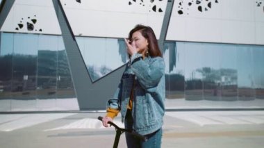 Scooter 'lı kot ceketli genç Asyalı kadın yaz parkında maske takıyor.