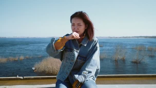 Young asian woman in a jeans jacket coughing and going out — Stock Video