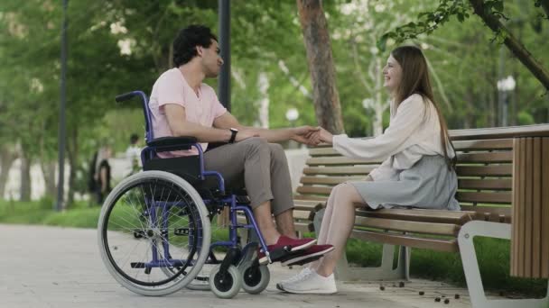 Χαρούμενος ανάπηρος σε αναπηρική καρέκλα και η κοπέλα του συναντιέται στο πάρκο. — Αρχείο Βίντεο