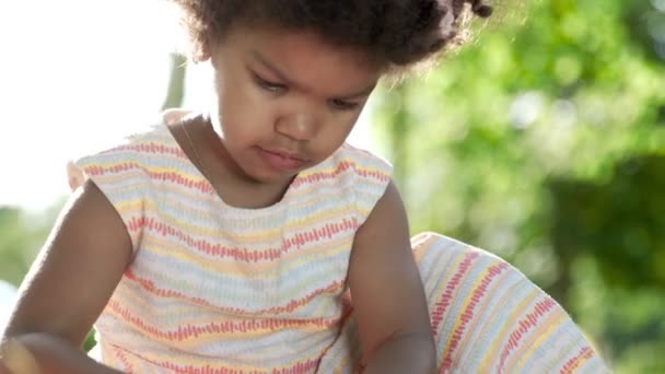 Pequena menina afro-americana jogar marcadores no parque — Vídeo de Stock