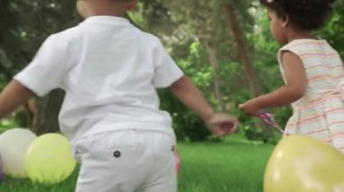 Küçük Afro-Amerikalı kız ve oğlan parkta renkli balonlarla oynuyorlar..