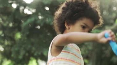 Küçük Afro-Amerikalı kız parkta sabun köpüğüyle oynuyor..