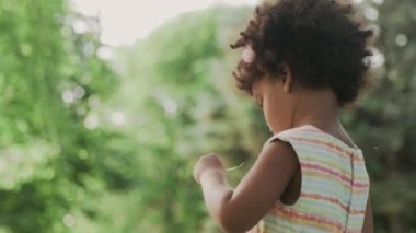 Küçük Afro-Amerikalı kız parkta büyüteçle oynuyor..