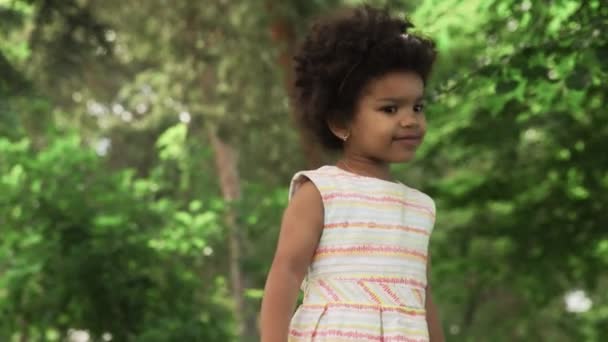 Niña afroamericana jugando con burbujas de jabón en el parque . — Vídeo de stock