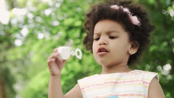 Close up of african-american girl blow soap bubbles in the park. — Stock Video