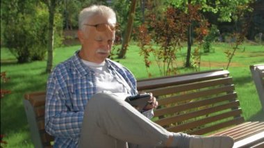 Parkta tablet bilgisayarı olan yakışıklı bir ihtiyar.