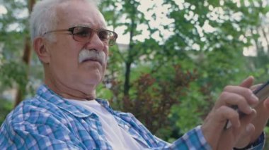 Bıyıklı yaşlı bir adam cep telefonundan mesaj görmeye çalışıyor ama...