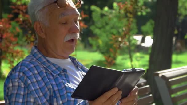 Vista lateral del anciano con bigote entiende cómo abrir la aplicación en el ordenador tableta. Habla consigo mismo. — Vídeo de stock