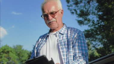 Bıyıklı yaşlı bir adam kitapta komik anlar okuyor. Yaşlı adam parkta bankta oturuyor ve kitap okuyor.