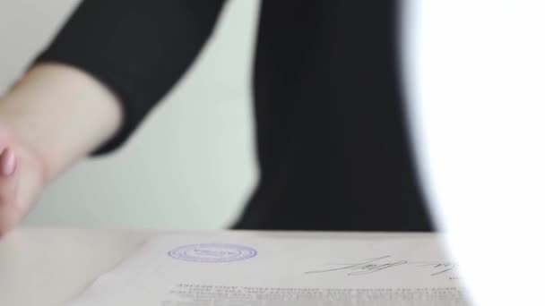 Женская рука, которая ставит штамп Утвержденный в договоре или документах . — стоковое видео