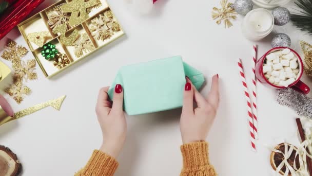 Woman wrapping christmas present, gift on white table background with holiday decorations. — Stock Video