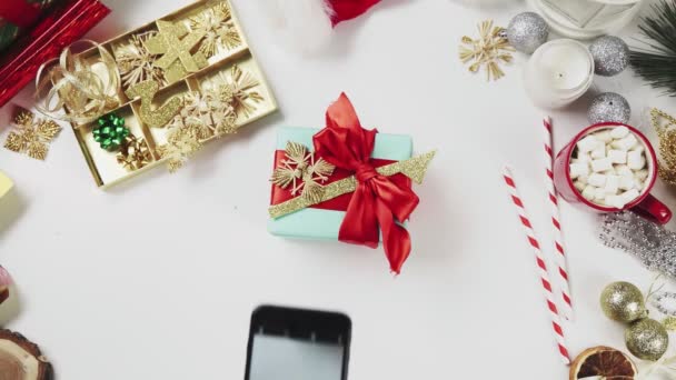 Frau von oben fotografiert Weihnachtsgeschenk auf weißem Tisch — Stockvideo