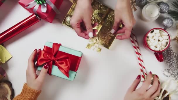 Dos mujeres envolviendo regalo de Navidad, regalo sobre fondo de mesa blanca con decoraciones navideñas . — Vídeos de Stock