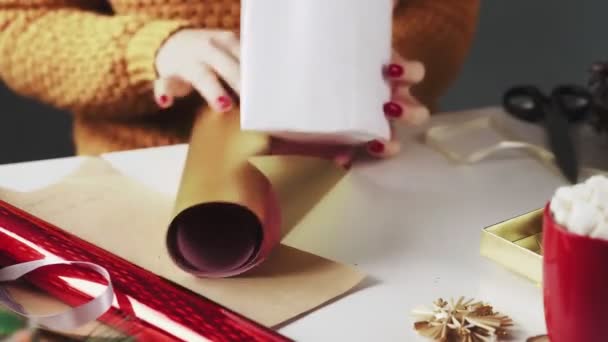 Frau verpackt handgemachtes Weihnachtsgeschenk in goldenes Papier — Stockvideo