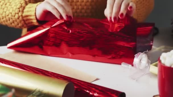 Mujer envolviendo Navidad regalo hecho a mano en papel rojo — Vídeo de stock
