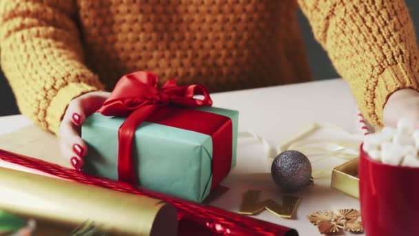 Молодая девушка пьет горячий шоколад с рождественскими подарками на столе — стоковое видео