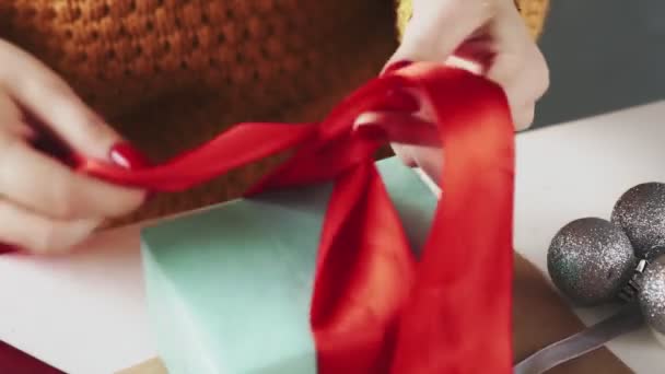 Close-up van vrouw koppelverkoop rood lint op kerstcadeau — Stockvideo