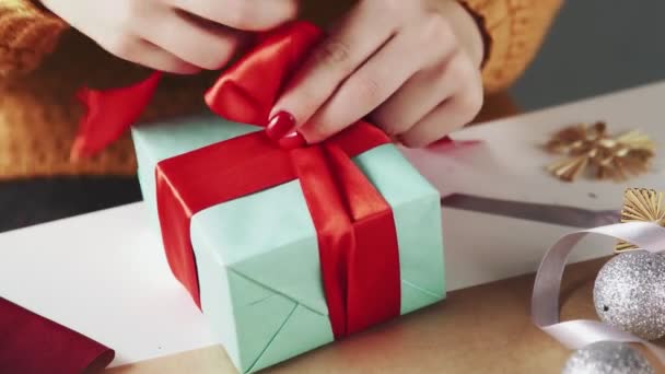 Primer plano de la mujer atando cinta roja en el regalo de Navidad — Vídeos de Stock