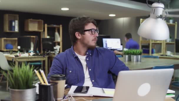 Πορτρέτο του νεαρού επιτυχημένου επιχειρηματία που κάθεται στο σύγχρονο γραφείο και κοιτάζει την κάμερα — Αρχείο Βίντεο