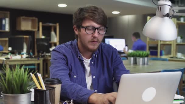 Homme créatif avec des lunettes boit un café tout en travaillant dans le bureau à l'ordinateur — Video
