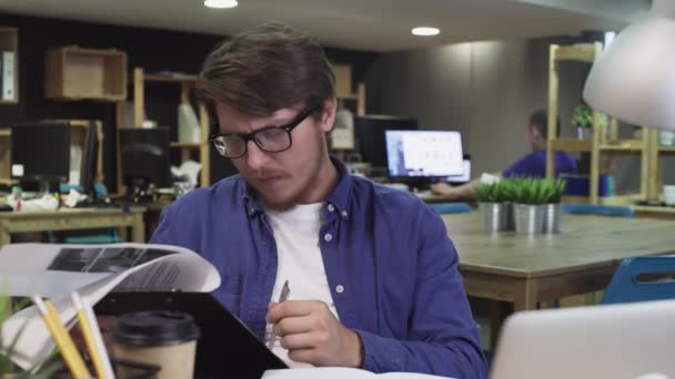 Молодий працівник, який працює з документами в офісі — стокове відео