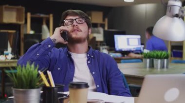 Genç İşadamı yaratıcı ofiste cep telefonuyla konuşuyor..