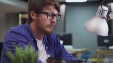 Ofisteki bilgisayarda çalışan programcının yan görünümü