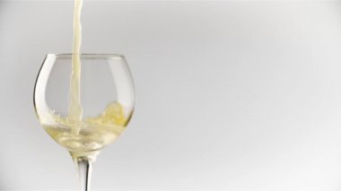 Beyaz zemin üzerinde şeffaf camlara dökülen portakal suyunun yavaş hareketi