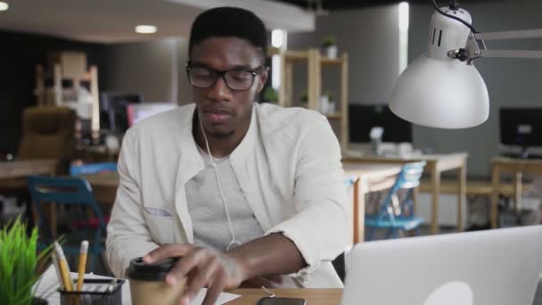 アフリカのビジネスマンはノートパソコンとドリンクコーヒーを使っています — ストック動画