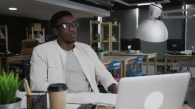 Çok çalışan siyahi Afrikalı iş adamı geceleri ofisinde çalışıyor.