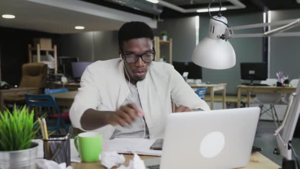 Młody Afrykanin pracuje na laptopie i pije kawę lub herbatę w biurze — Wideo stockowe