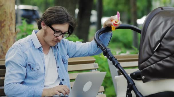 Freelancer sending laptop email and swinging stroller, family and career balance — Stock Video