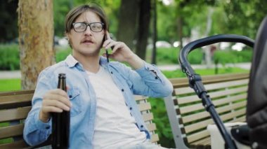 Babam telefonla konuşuyor ve bebek arabasının yanında bira içiyor.