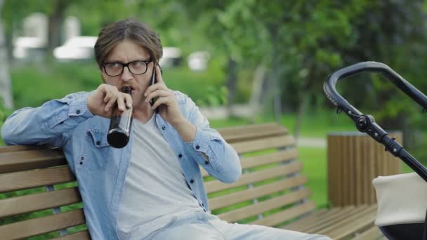 Side view of Father talking phone and drinking a beer near of baby stroller — Stock Video